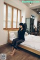 A woman sitting on a bed in a bedroom.