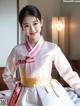 A woman in a white and pink hanbok posing for a picture.