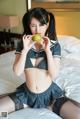 A woman in a school uniform eating an apple.