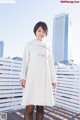 A woman in a white coat standing on a wooden deck.