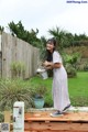 A woman standing on a wooden deck holding a watering can.