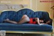 A woman laying on a blue couch in a room.