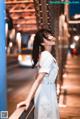 A woman in a white dress standing on a bridge.