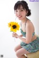 A woman sitting on a stool holding a sunflower.