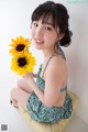 A woman sitting on a cushion holding a sunflower.