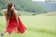 A woman in a red dress sitting in a field.