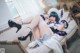 A woman in a maid outfit is sitting on a couch.