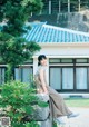 A woman sitting on a stone wall in front of a building.